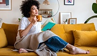a woman lounging on her couch with a book and tea
