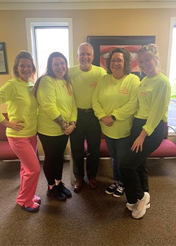 Collinsville dental team members posing in dental office wearing yellow shirts