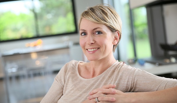 Woman sitting on a couch smiling with dental implants in Collinsville