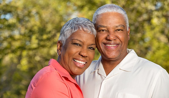 Smiling older man and woman holding each other outdoors