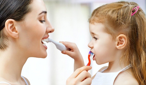 Mother teaching her child to brush their teeth