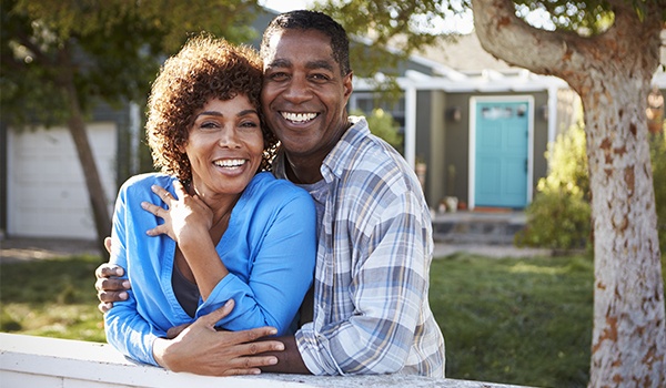 Man and woman smiling in their front yard after restorative dentistry in Collinsville