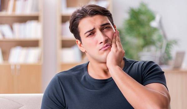 Man who needs a root canal in Collinsville holding his jaw in pain