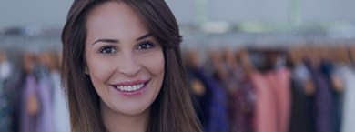 Woman smiling in front of a rack of clothes