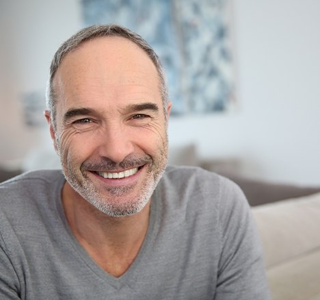 Smiling man in gray sweater sitting in a living room