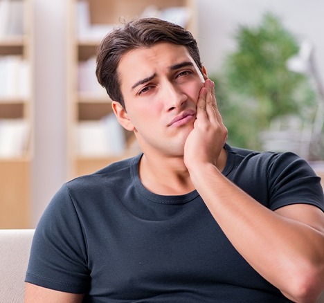 Man sitting down and holding his jaw in pain