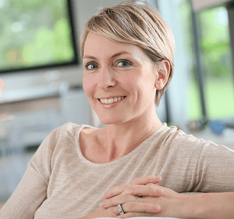 Woman smiling with her finger locked over the back of her chair