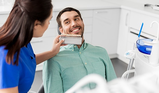 Dental assistant holding shade scale to patient's smile
