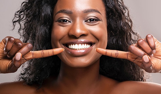 Smiling woman pointing to her white teeth