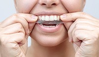 Person placing whitening strip on teeth