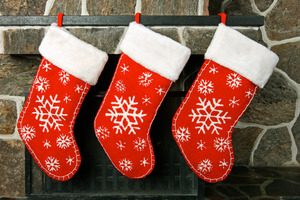 Three snowflake-patterned stockings by a fireplace