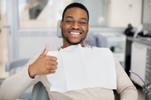 Man smiling and giving thumbs up after whitening treatment